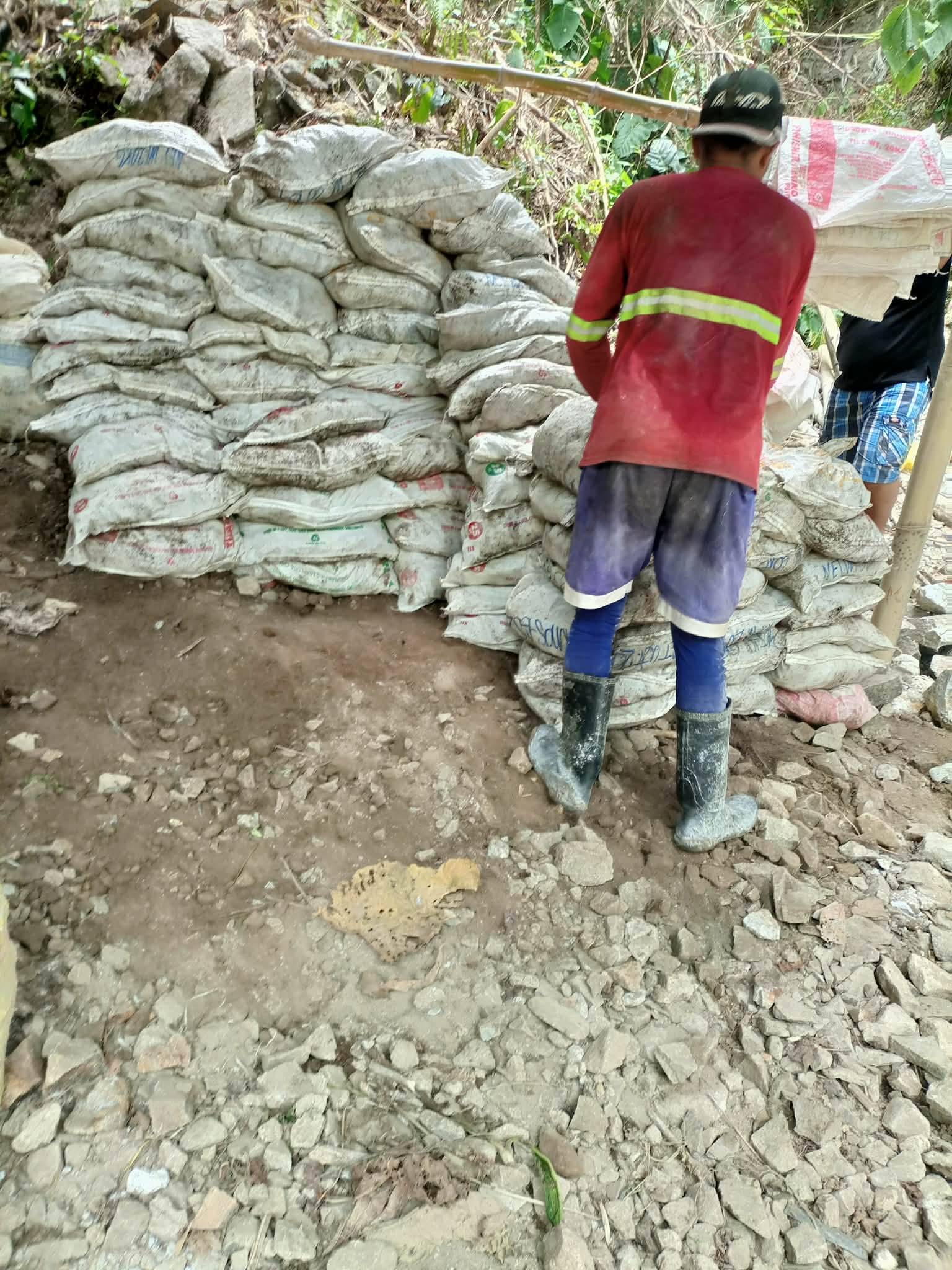 A local miner standing beside organized bags of mineral material