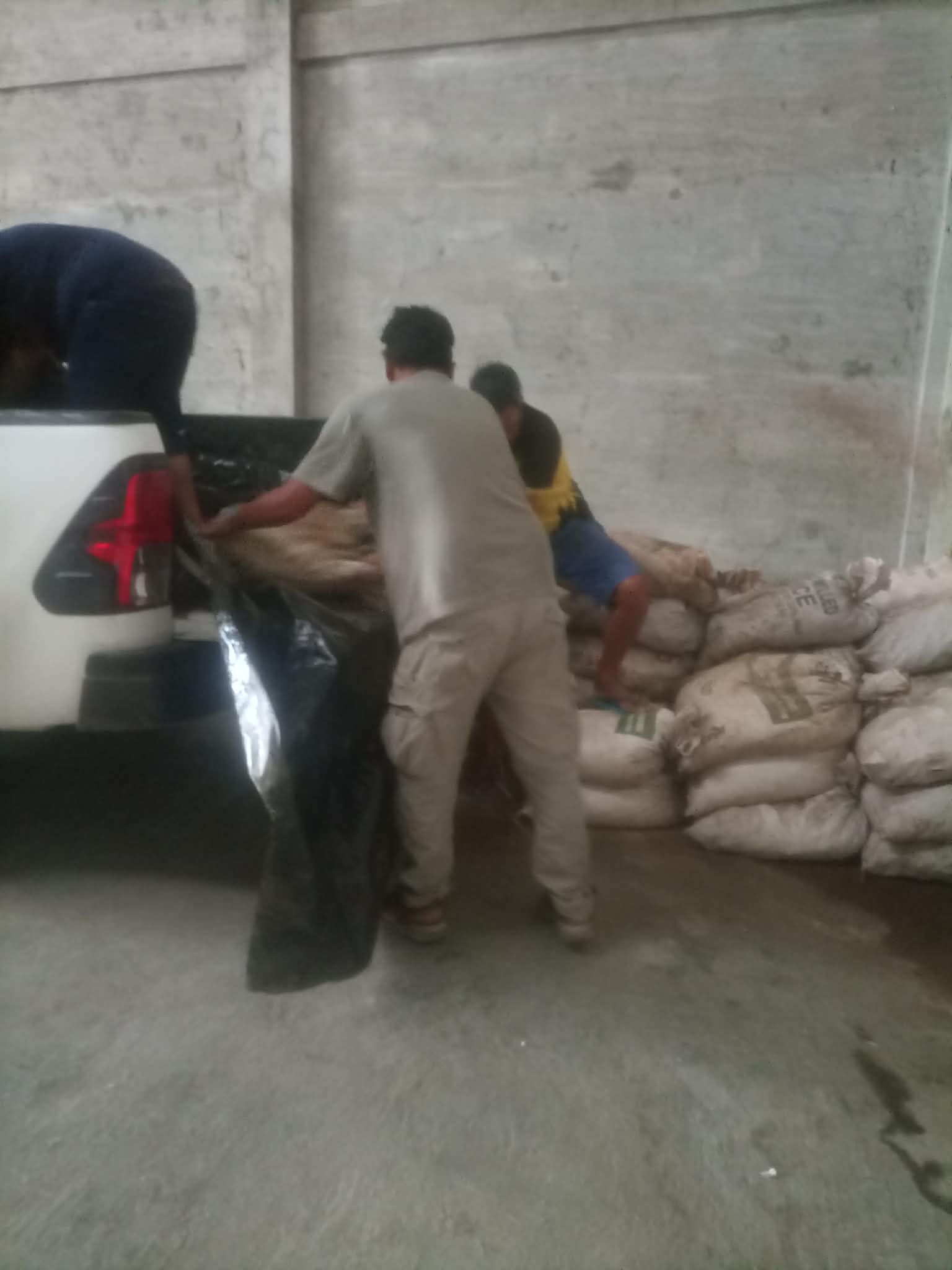 Supplier representatives handling bagged mineral material inside a warehouse
